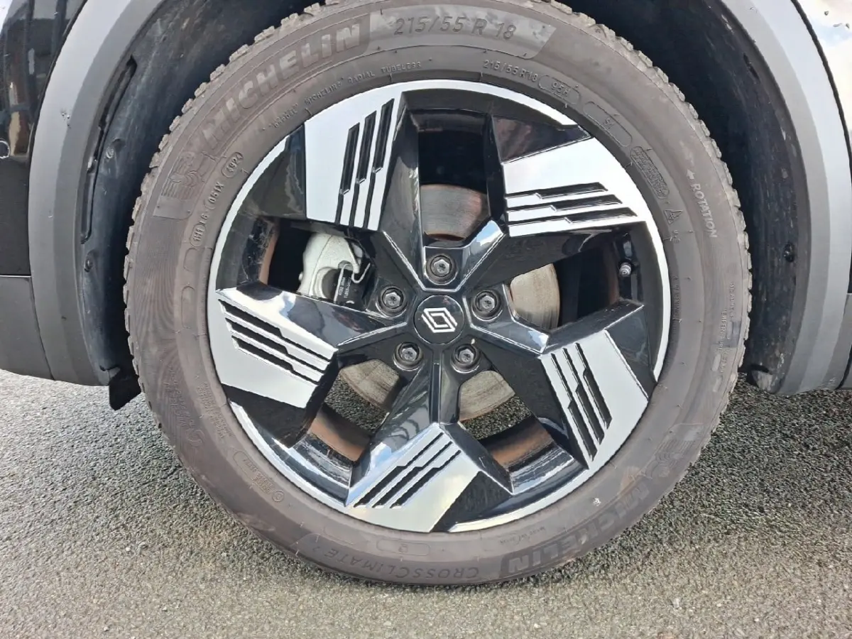 Gros plan sur la roue avant gauche de la Renault SYMBIOZ noire, jante alliage noire et argentée au design géométrique.