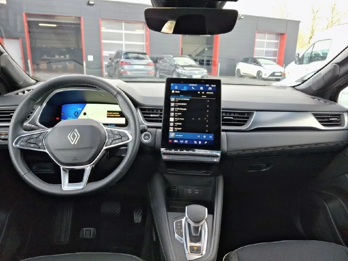 Vue intérieure avant du tableau de bord noir de la Renault SYMBIOZ avec écran tactile vertical et volant multifonctions.