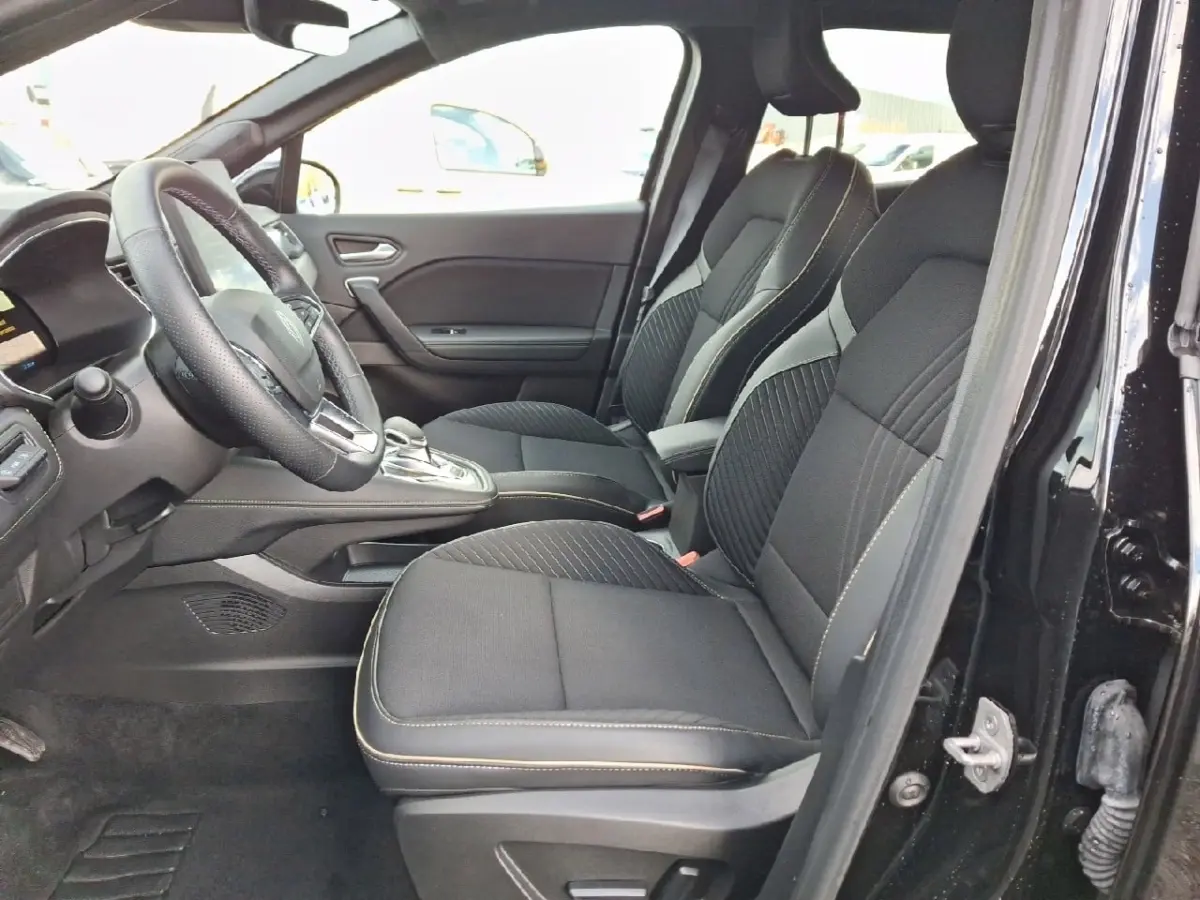 Vue intérieure côté gauche du Renault Symbioz noir, sièges avant en tissu avec surpiqûres contrastées et volant multifonctions.