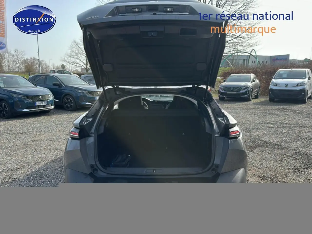 Vue arrière d'une Peugeot 408 Hybrid 145 allure gris sélénite avec coffre ouvert, montrant l'espace de chargement.
