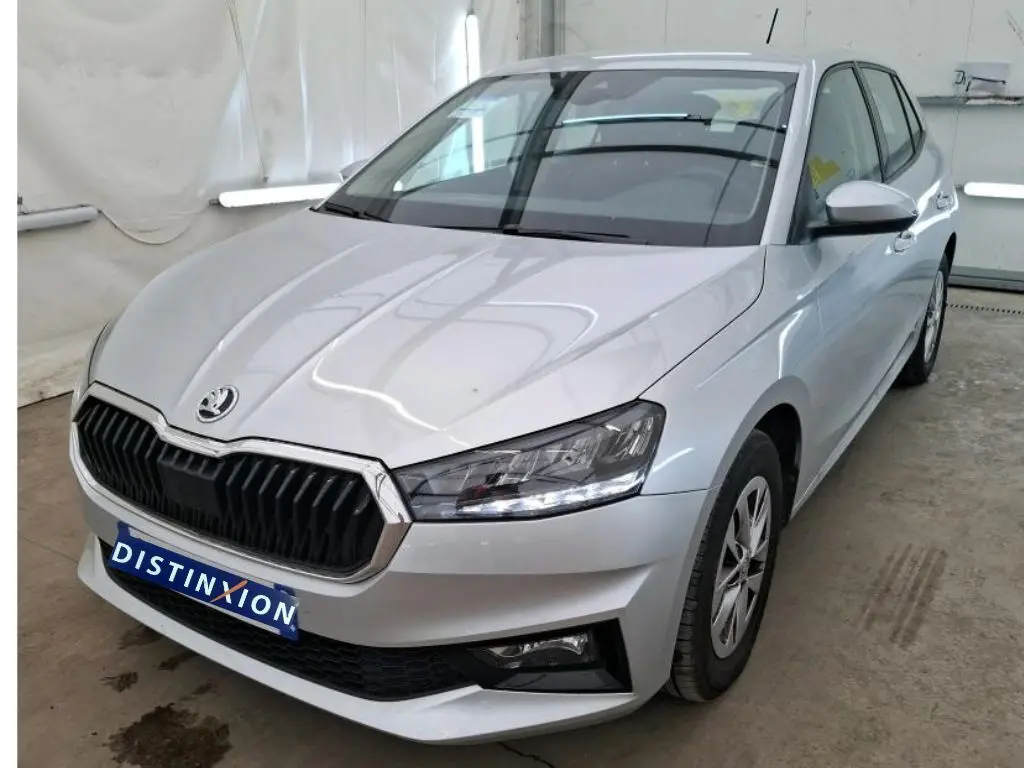 Vue 3/4 avant droite d'une Skoda Fabia Ambition gris clair 2023 avec calandre noire et phares LED allumés.