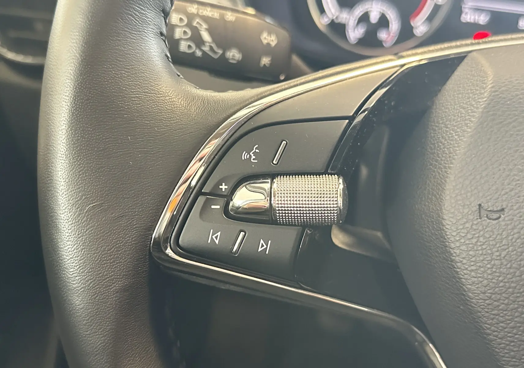 Gros plan sur la commande de volume argentée et boutons multifonctions du volant noir de la Skoda Fabia gris 2023.