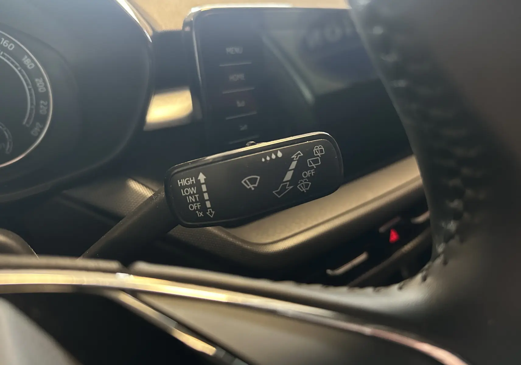 Gros plan sur la commande d’essuie-glace à gauche du volant dans l’habitacle gris du Skoda Fabia Ambition 2023.