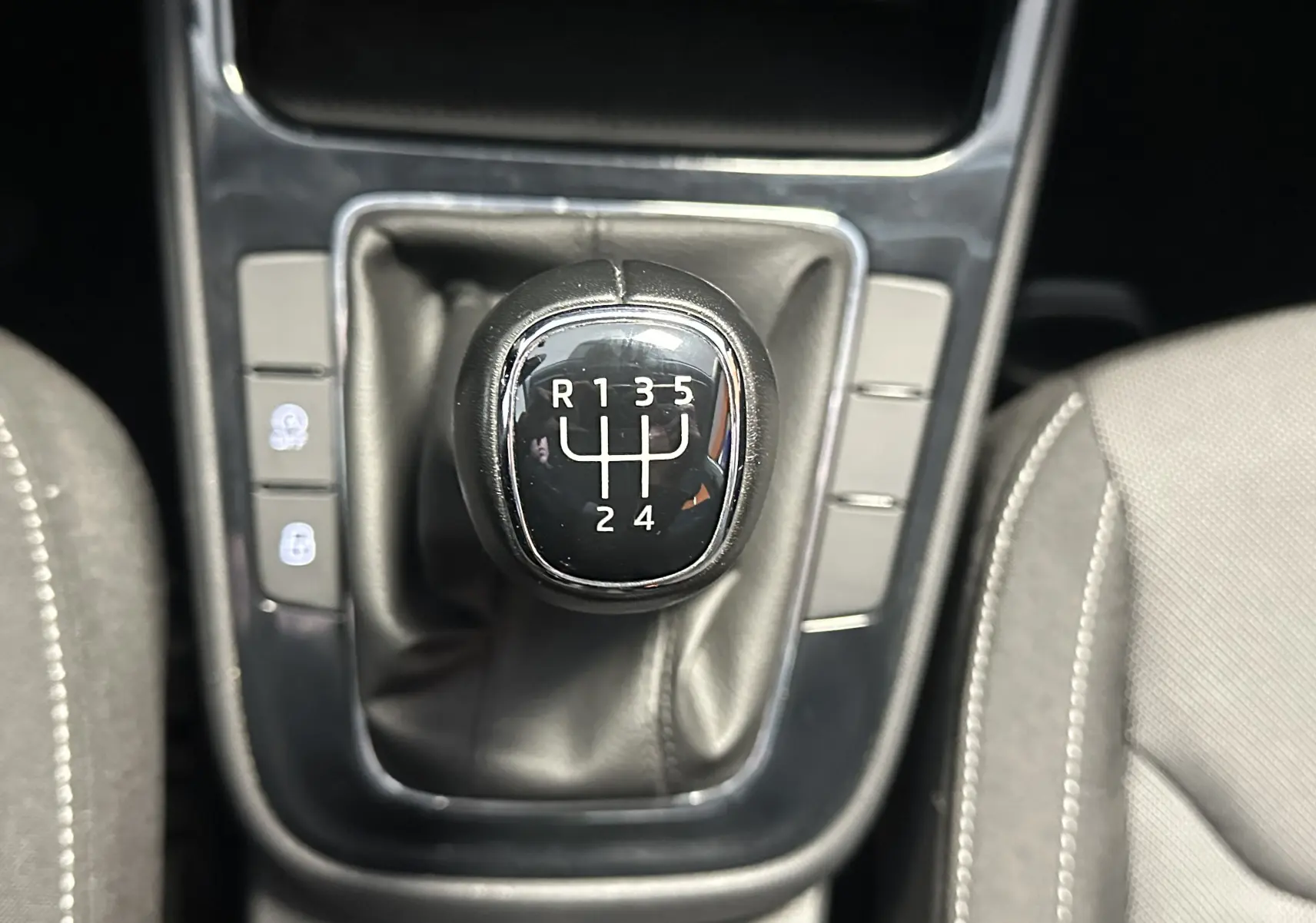 Gros plan sur le levier de vitesse manuel noir de la Skoda Fabia Ambition 2023, entouré de sièges gris clair.