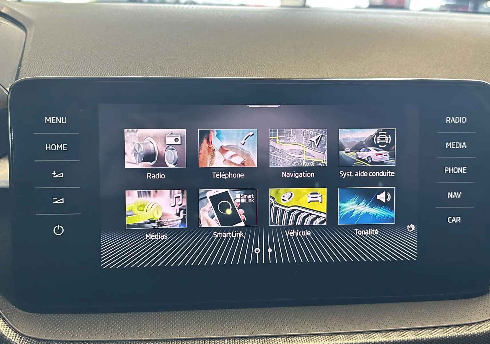 Écran tactile central de la Skoda Fabia Ambition 2023 gris, affichant le menu principal avec options multimédia et navigation.