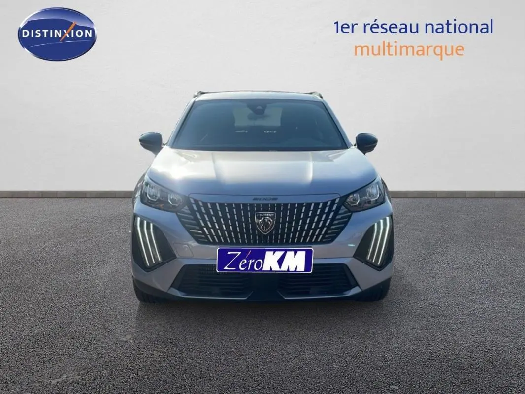 Vue frontale d'un Peugeot 2008 gris 2025 avec calandre distinctive et feux diurnes LED allumés.