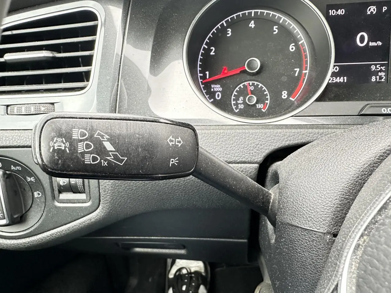 Gros plan sur la manette de clignotant à gauche du volant dans l’habitacle gris foncé d’une Volkswagen Golf VII 2018.