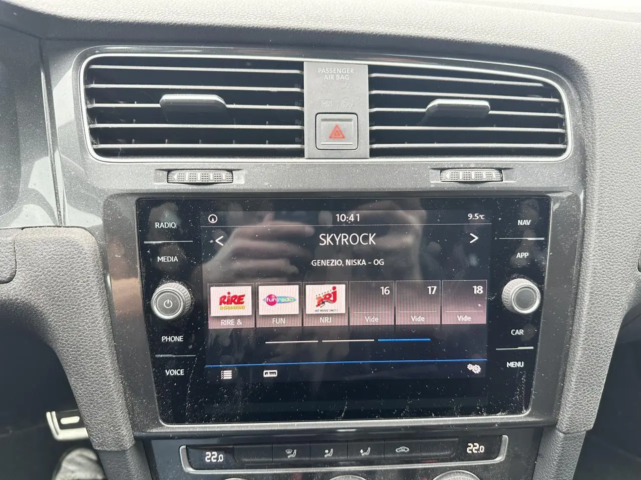 Vue rapprochée de l’écran tactile central du tableau de bord d’une Volkswagen Golf VII gris foncé, affichant la radio Skyrock.