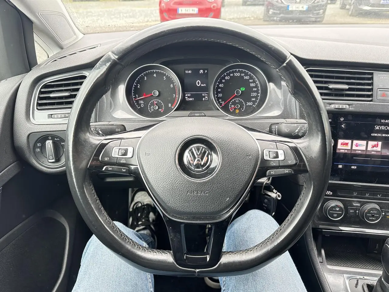 Vue intérieure centrée sur le volant en cuir noir d'une Volkswagen Golf VII avec tableau de bord et écran tactile visibles.