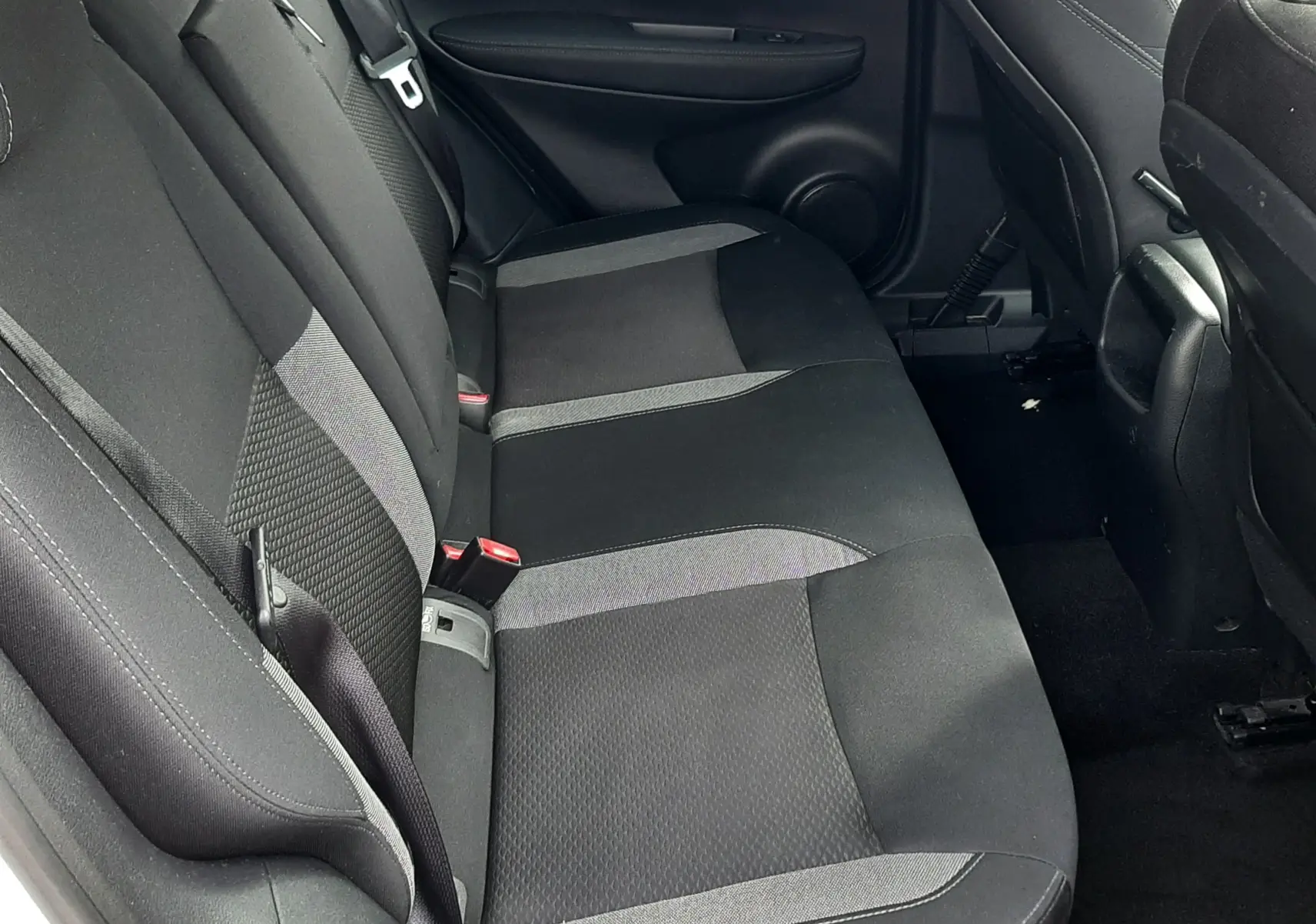 Vue intérieure côté gauche des sièges arrière en tissu gris et noir du Nissan Qashqai blanc 2018, avec ceinture de sécurité visible.
