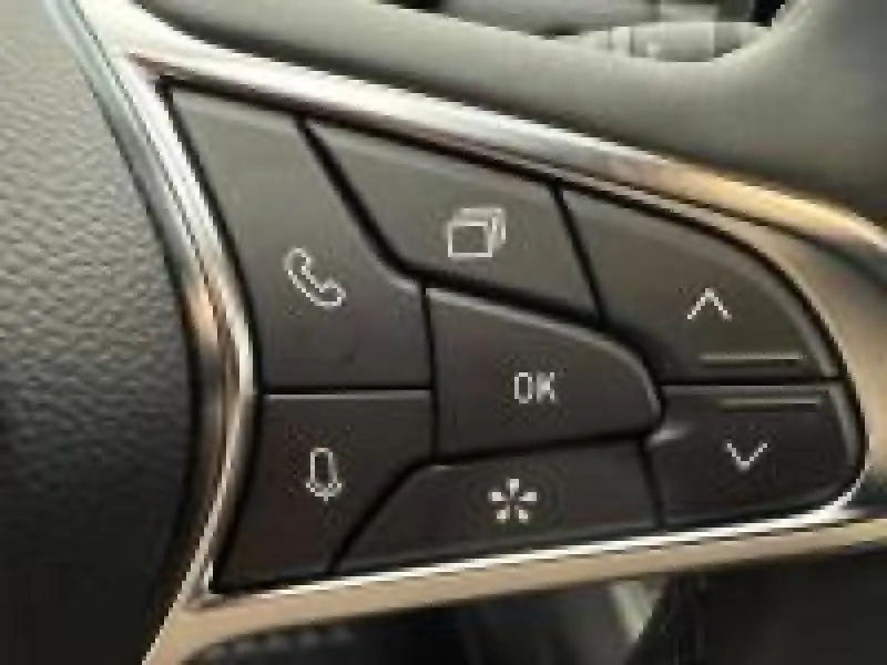 Gros plan sur les commandes multifonctions noires du volant du Renault Captur rouge, avec boutons appel et navigation.
