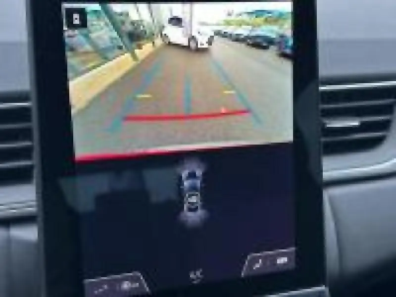 Écran tactile intérieur montrant la caméra de recul et l'aide au stationnement du Renault Captur rouge 2025.