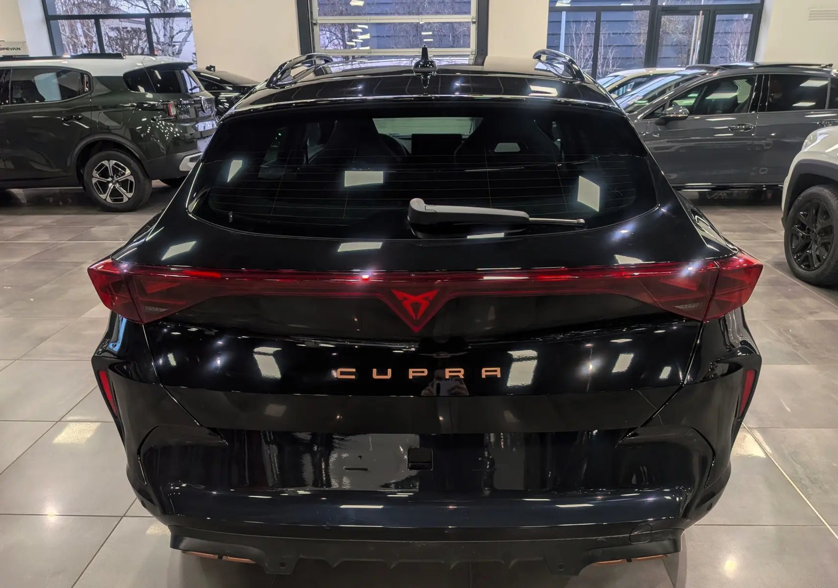 Vue arrière d'une CUPRA Formentor eHybrid 2025 en noir minuit, avec feux arrière reliés et logo CUPRA lumineux.
