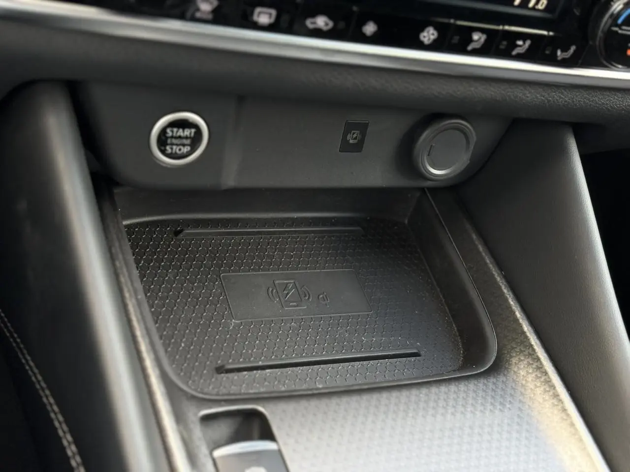Gros plan sur la console centrale noire du Nissan Qashqai 2025 avec bouton Start/Stop et chargeur sans fil.
