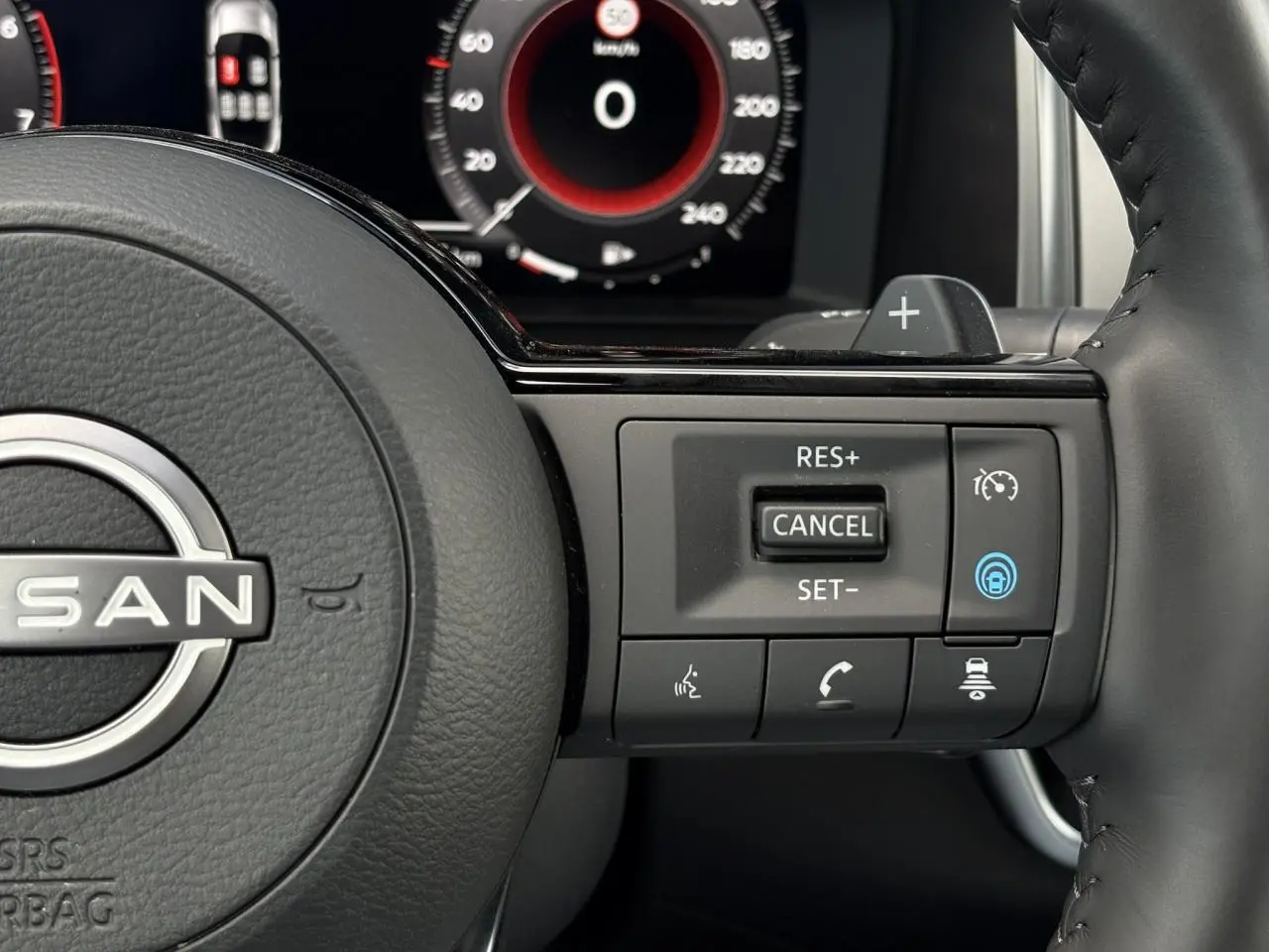 Gros plan sur le volant cuir noir du Nissan Qashqai 2025 avec commandes de régulateur adaptatif et tableau de bord numérique.