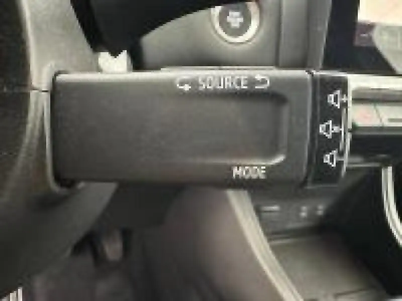 Gros plan sur la commande au volant noire avec boutons source et mode du Renault Captur rouge 2025.