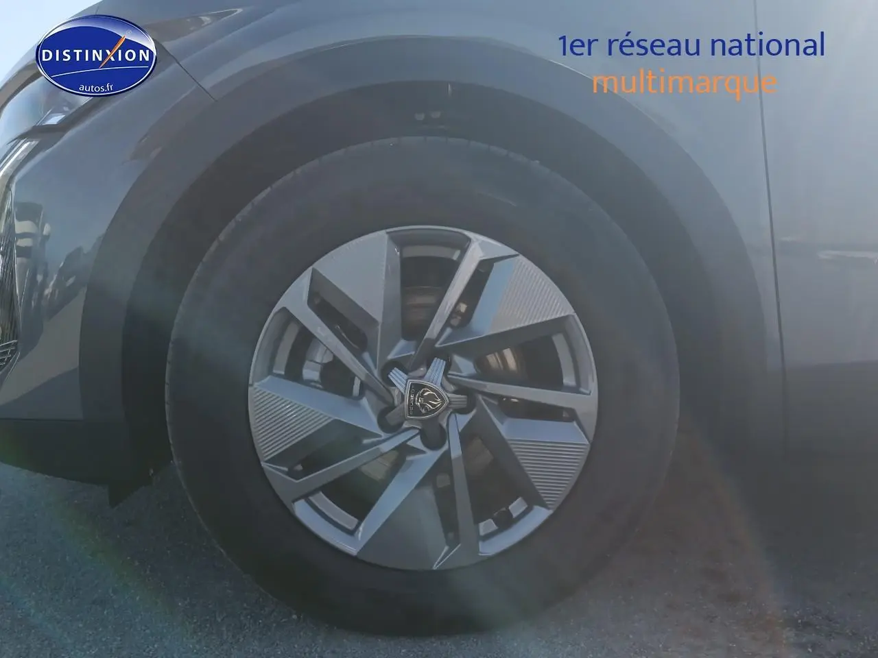 Gros plan sur la roue avant gauche de la Peugeot 408 Hybrid 145 allure e-dcs6 gris sélénite avec jante alu au design moderne.