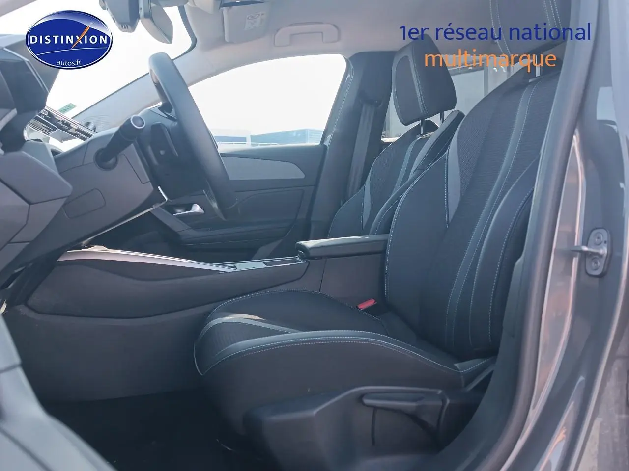 Vue intérieure côté conducteur de la Peugeot 408 Hybrid 145 allure gris sélénite, mettant en valeur les sièges et l'accoudoir central.