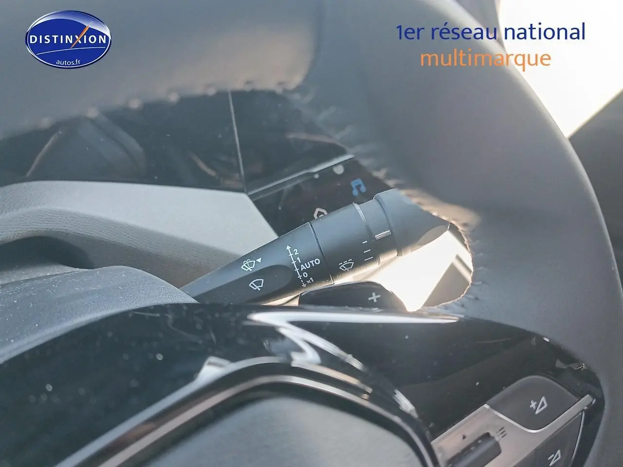 Gros plan sur la manette de commande des essuie-glaces derrière le volant cuir d'une Peugeot 408 gris sélénite.