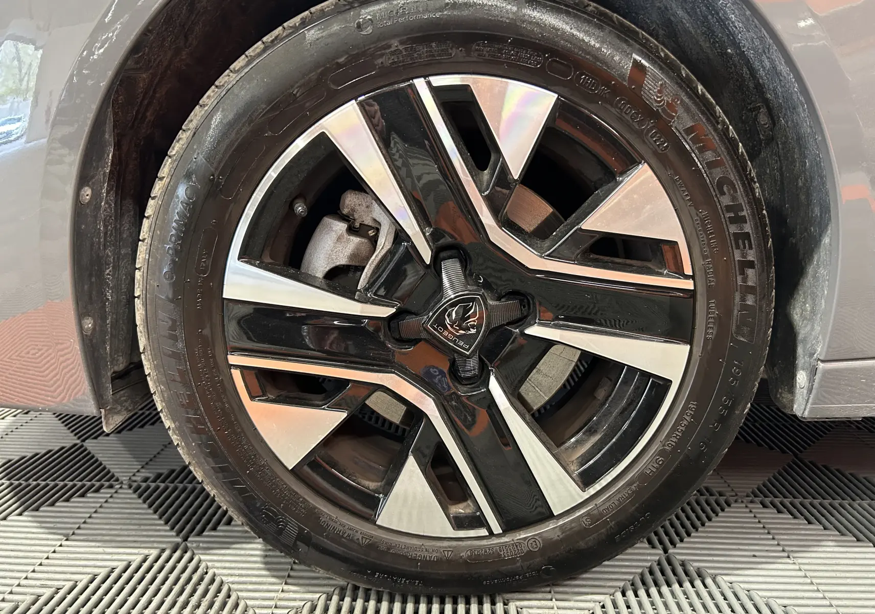 Gros plan sur la jante alliage bicolore noire et argentée d'une Peugeot 208 gris Selenium, avec pneu Michelin visible.