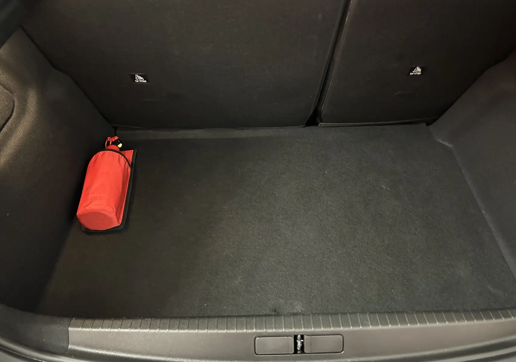 Coffre ouvert de la Peugeot 208 gris Selenium, vue plongeante montrant un extincteur rouge posé à gauche.