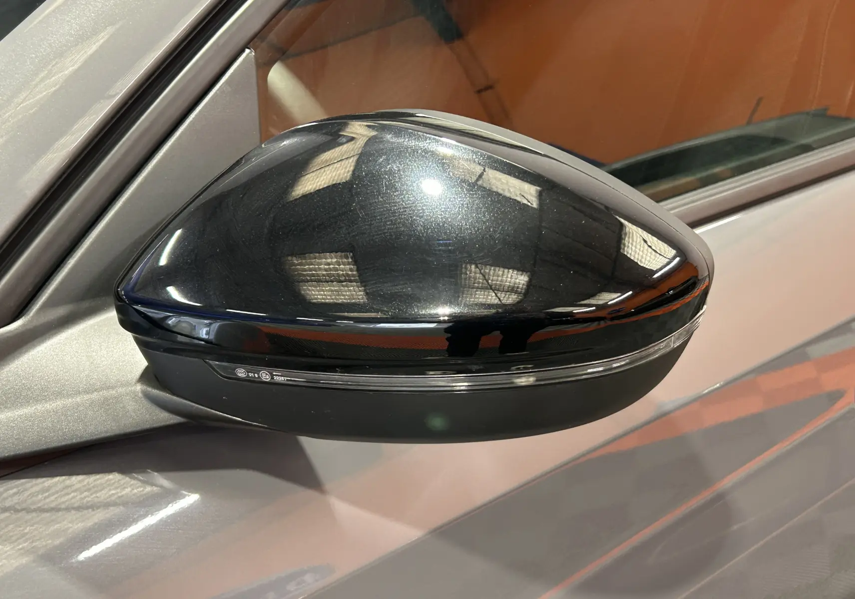 Rétroviseur noir brillant côté gauche d'une Peugeot 208 gris Selenium, vue rapprochée sur la portière.