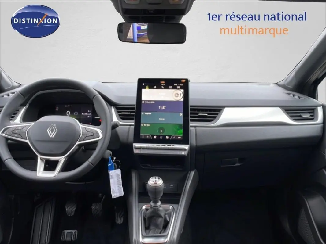 Vue intérieure frontale du tableau de bord noir du Renault Captur 2025 avec écran tactile vertical et volant multifonctions.