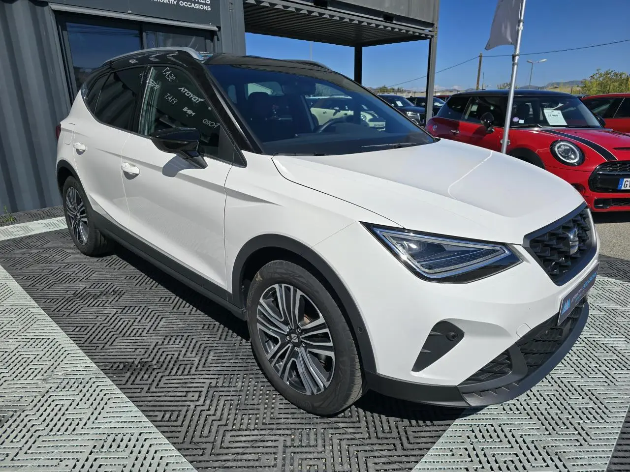 SEAT Arona blanc toit noir en 3/4 avant droit, avec calandre FR et jantes alliage 17 pouces visibles.