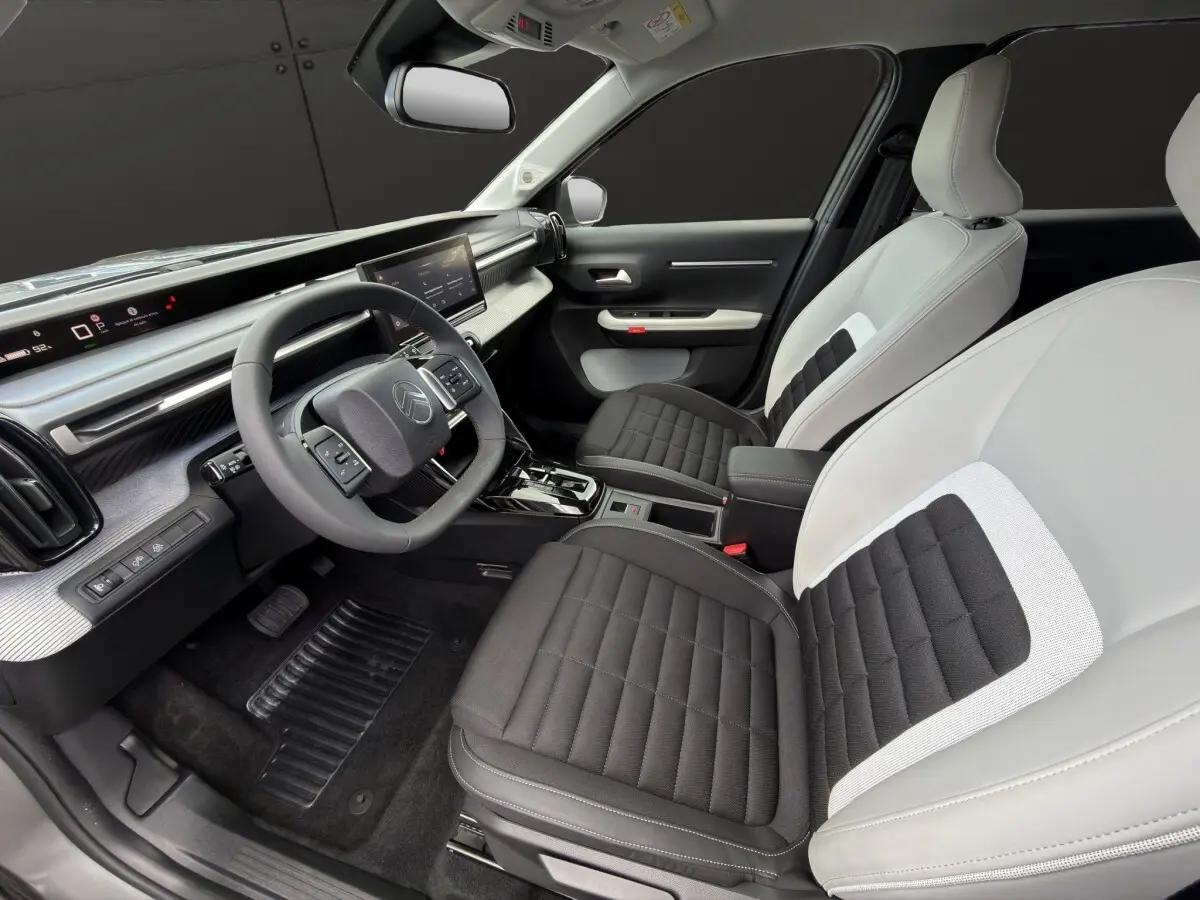 Intérieur avant droit du Citroën C3 Aircross électrique 2025, sièges bicolores noir et gris, tableau de bord moderne avec écran tactile.