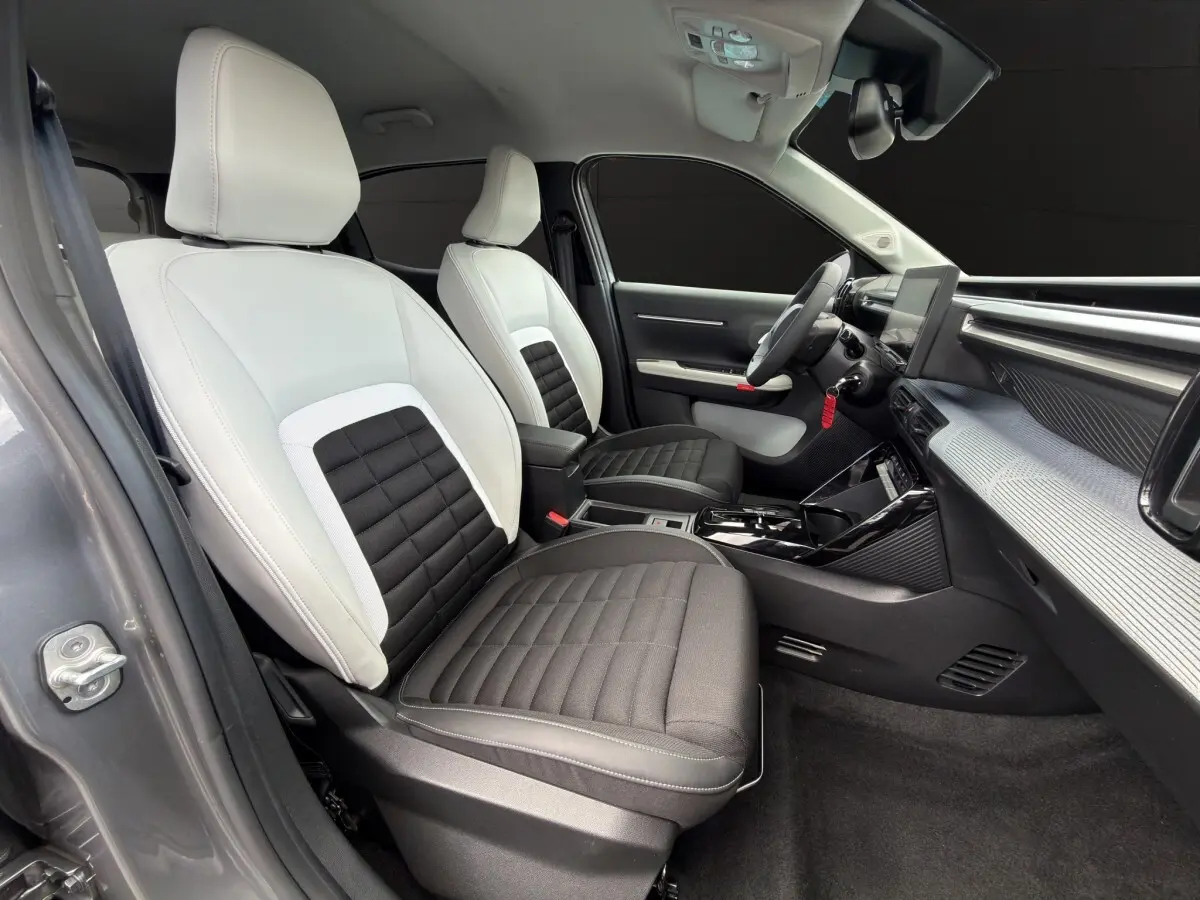 Vue intérieure côté conducteur de la Citroën C3 Aircross électrique 2025, sièges bicolores noirs et blancs, tableau de bord moderne.
