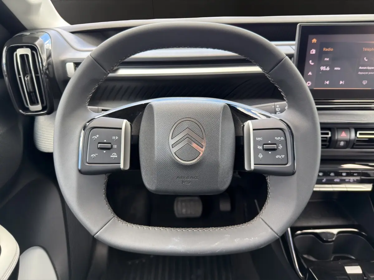Vue rapprochée du volant cuir noir du Citroën C3 Aircross 2025 avec commandes multifonctions et tableau de bord tactile.