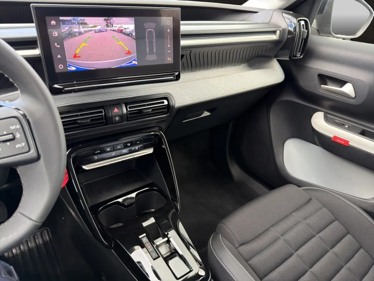 Vue intérieure côté passager du tableau de bord et console centrale noire du Citroën C3 Aircross gris foncé 2025 électrique.