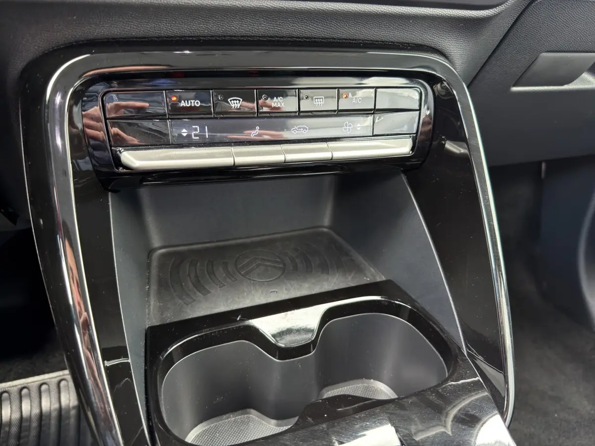 Détail du tableau de bord central noir avec commandes climatisation et zone de recharge sans fil du Citroën C3 Aircross 2025.