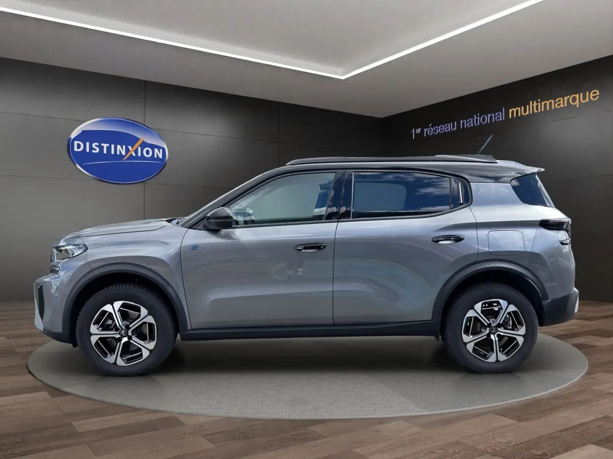Vue de profil côté gauche d'un Citroën C3 Aircross électrique gris foncé avec jantes distinctives et rails de toit noirs.