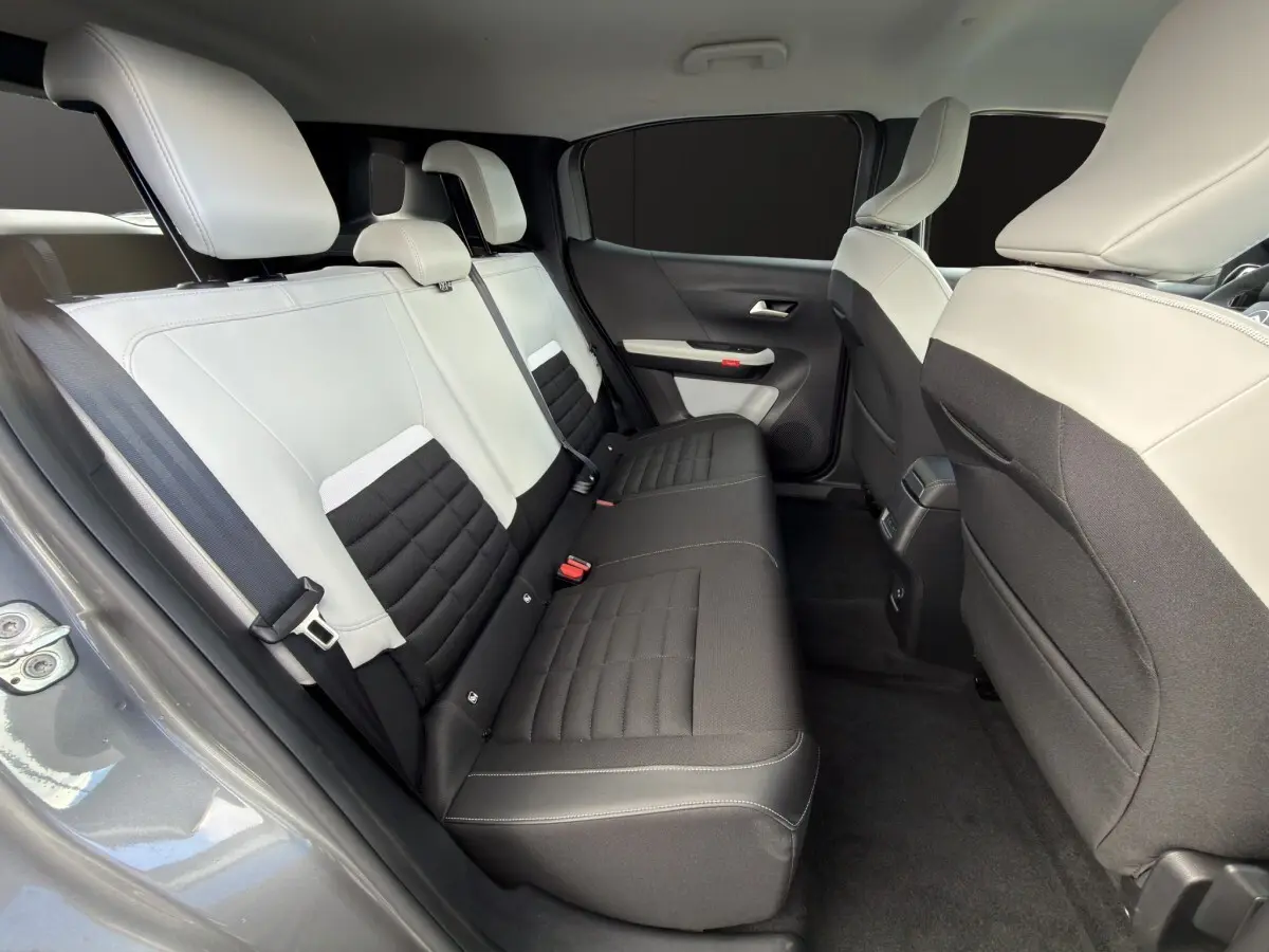 Vue intérieure côté gauche sur la banquette arrière bicolore gris clair et noir du Citroën C3 Aircross électrique gris foncé.