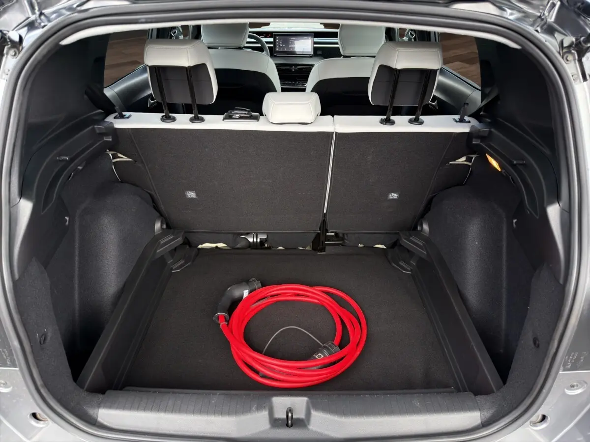 Coffre ouvert d'une Citroën C3 Aircross gris foncé, vue arrière, avec câble de charge électrique rouge visible.