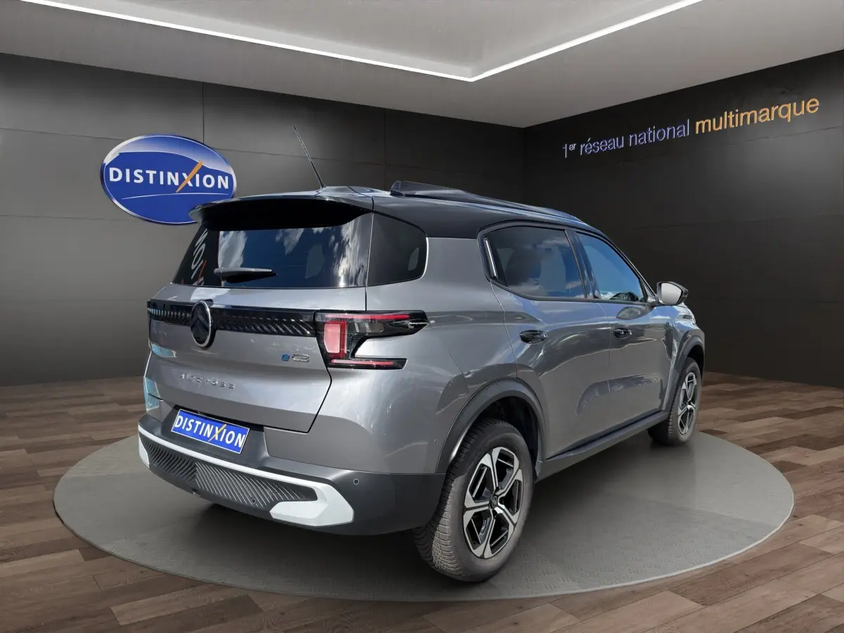 Vue 3/4 arrière droite d'une Citroën C3 Aircross électrique gris foncé avec toit noir et jantes distinctives.