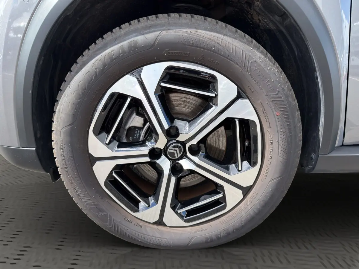 Gros plan sur la roue avant droite du Citroën C3 Aircross électrique gris foncé avec jante alliage bicolore moderne.