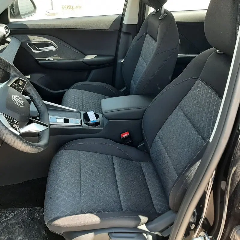 Vue intérieure côté conducteur du MG ZS 1.5 L Hybrid+ 2026 avec sièges tissu gris et console centrale noire.