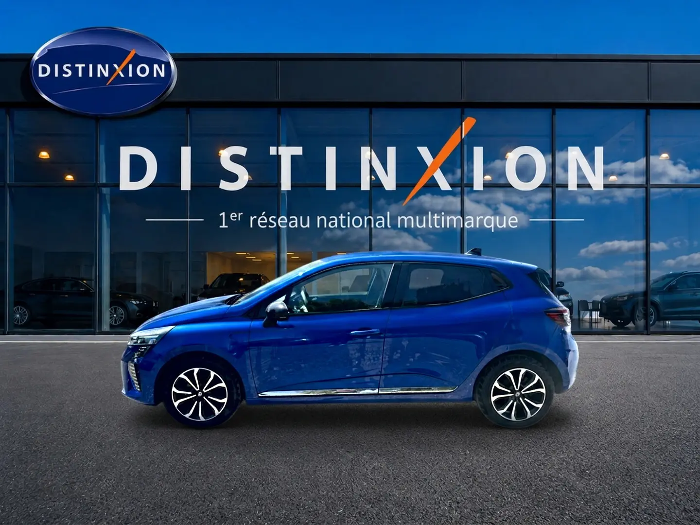 Profil droit d'une Renault Clio V bleu iron garée devant une vitrine avec logo Distinxion.