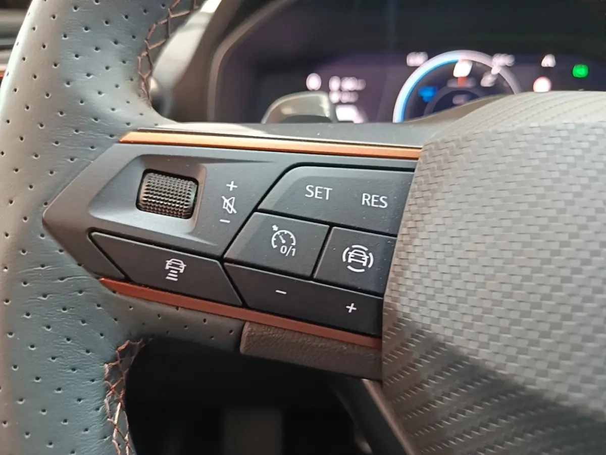 Gros plan sur les commandes gauche du volant perforé noir du CUPRA Formentor 2024 avec surpiqûres orange.