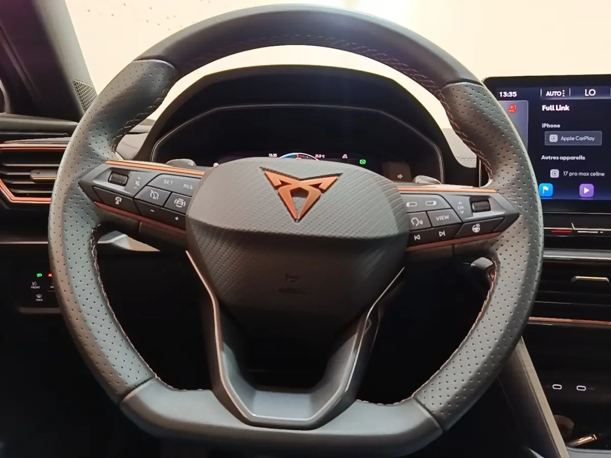 Vue rapprochée du volant en cuir noir perforé du CUPRA Formentor 1.4 e-HYBRID avec commandes intégrées et logo cuivré.