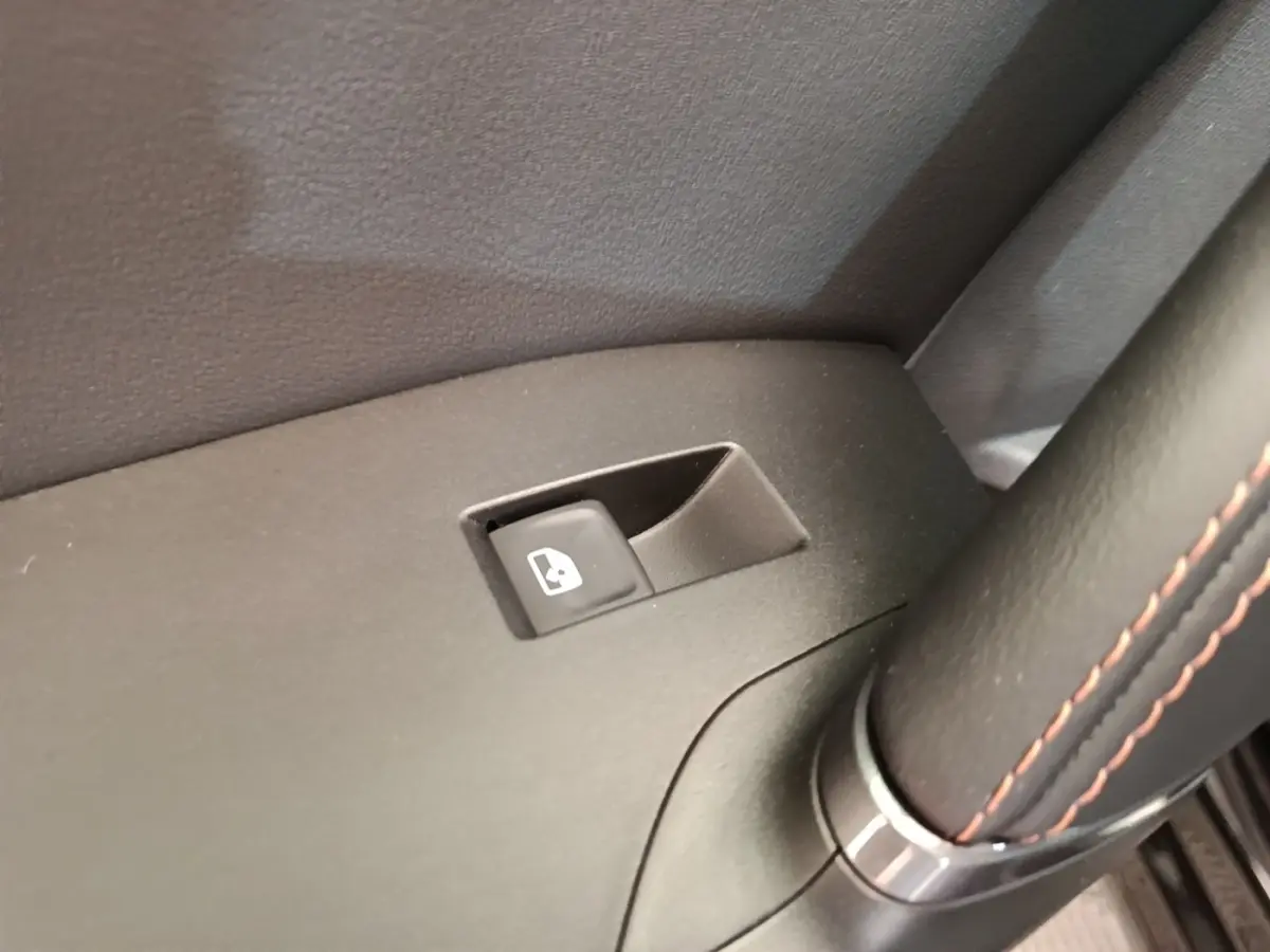Gros plan sur le bouton de commande de lève-vitre côté conducteur dans l'habitacle noir du CUPRA Formentor 2024.