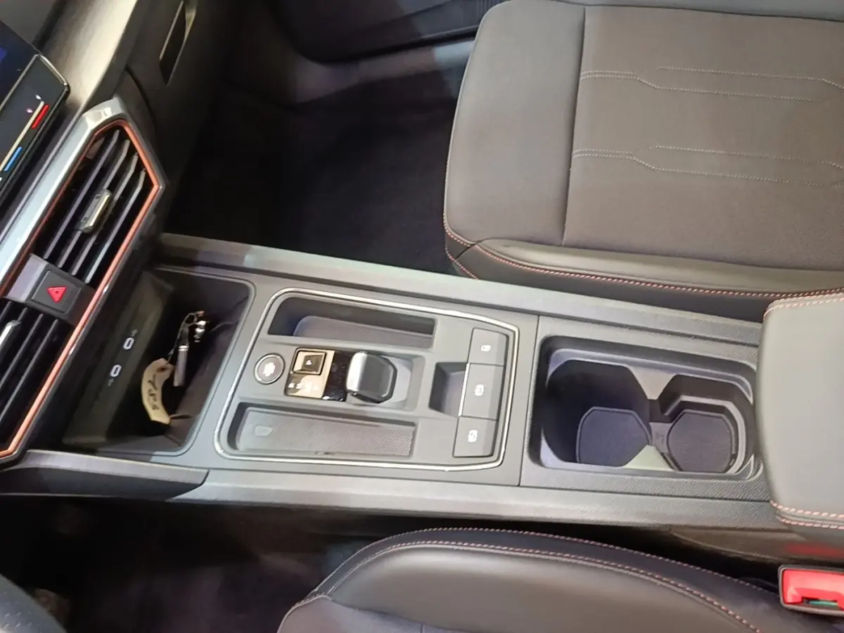 Vue plongeante sur la console centrale noire du CUPRA Formentor 1.4 e-HYBRID avec sélecteur de boîte auto et porte-gobelets.