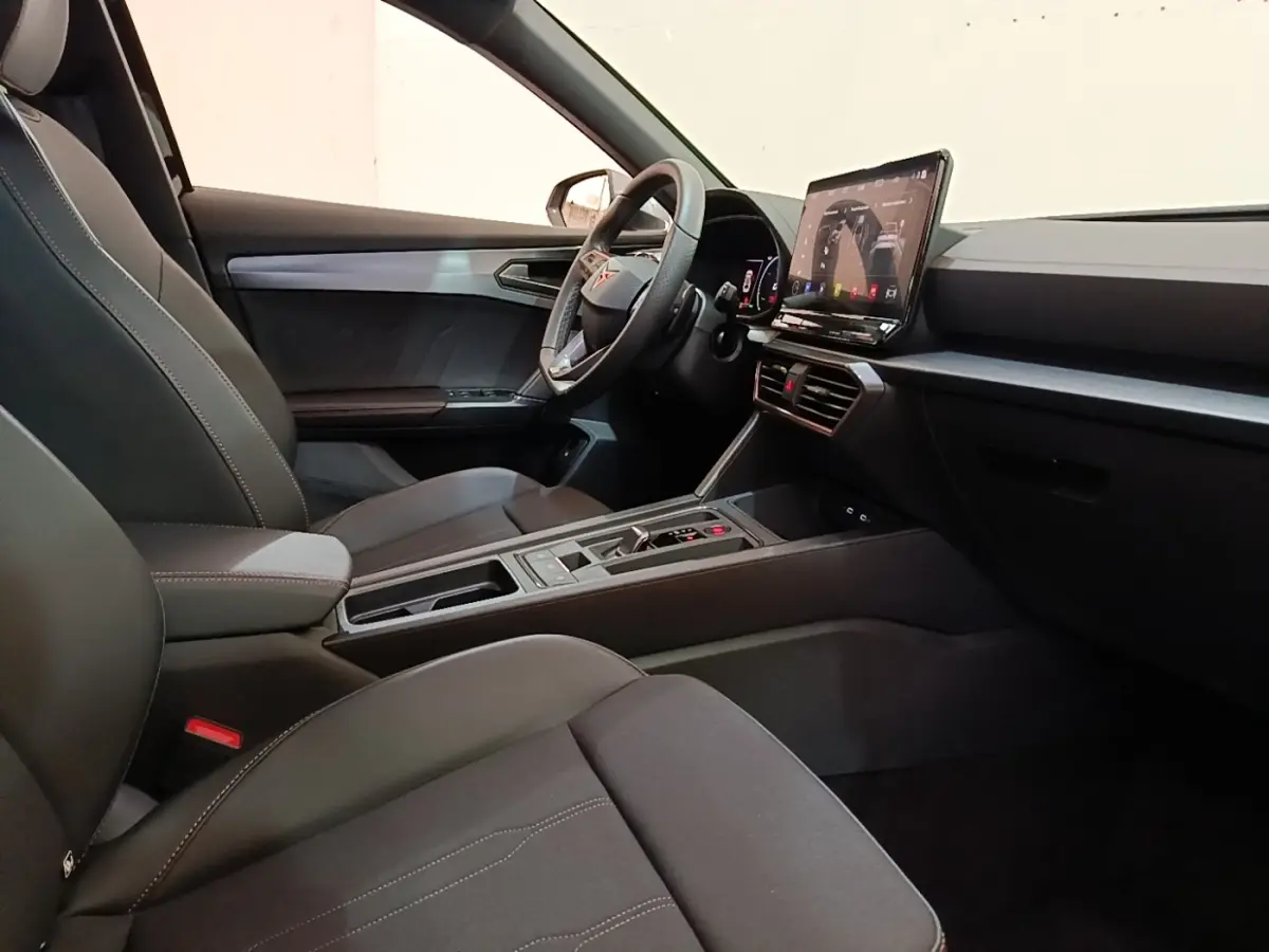 Intérieur noir du CUPRA Formentor 1.4 e-HYBRID 2024, vue côté conducteur avec écran tactile central et volant cuir.