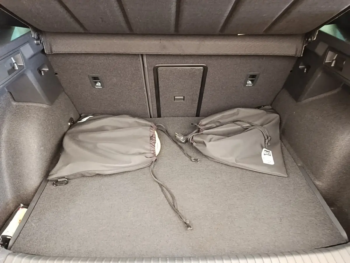 Coffre spacieux du CUPRA Formentor noir 2024, vue intérieure avec tapis gris et deux sacs de rangement noirs.