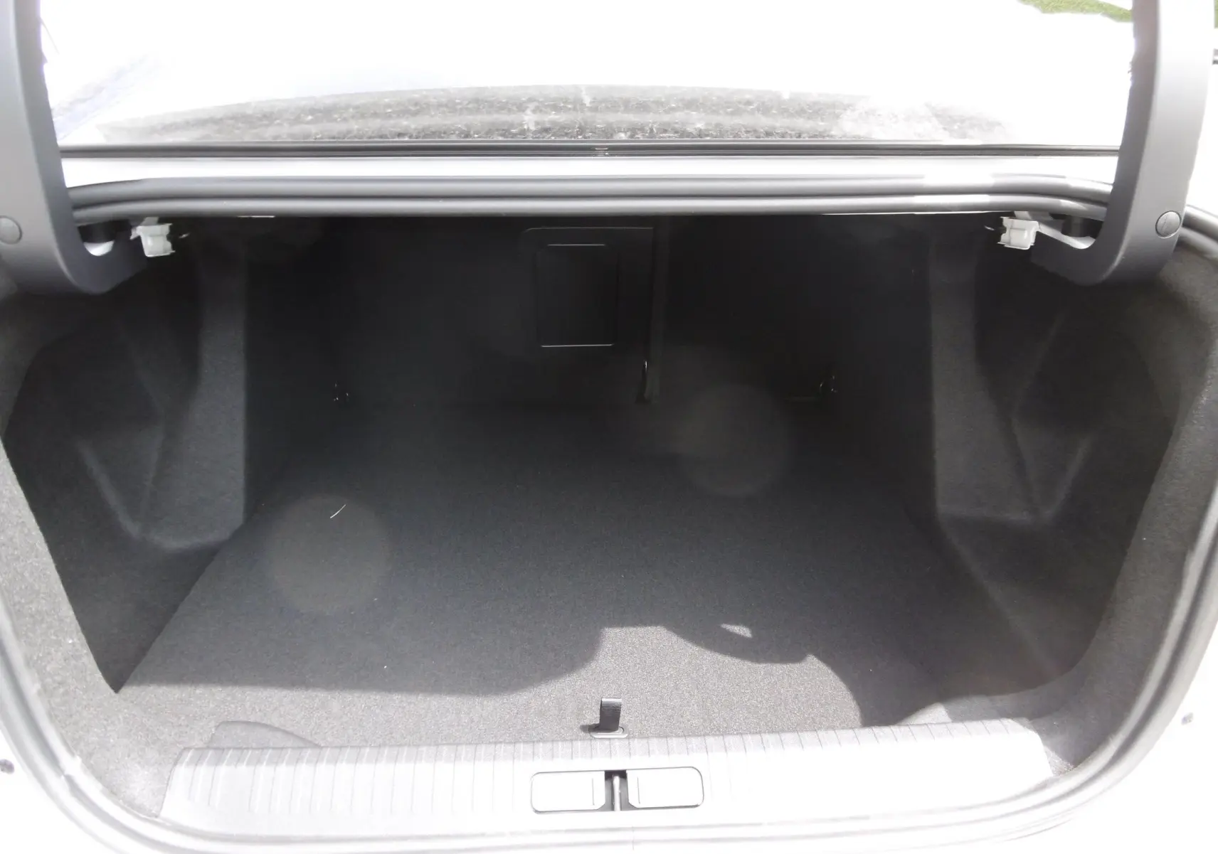 Coffre ouvert vu de l'arrière d'une Citroën C4 X blanc polaire, espace de chargement vide et propre.