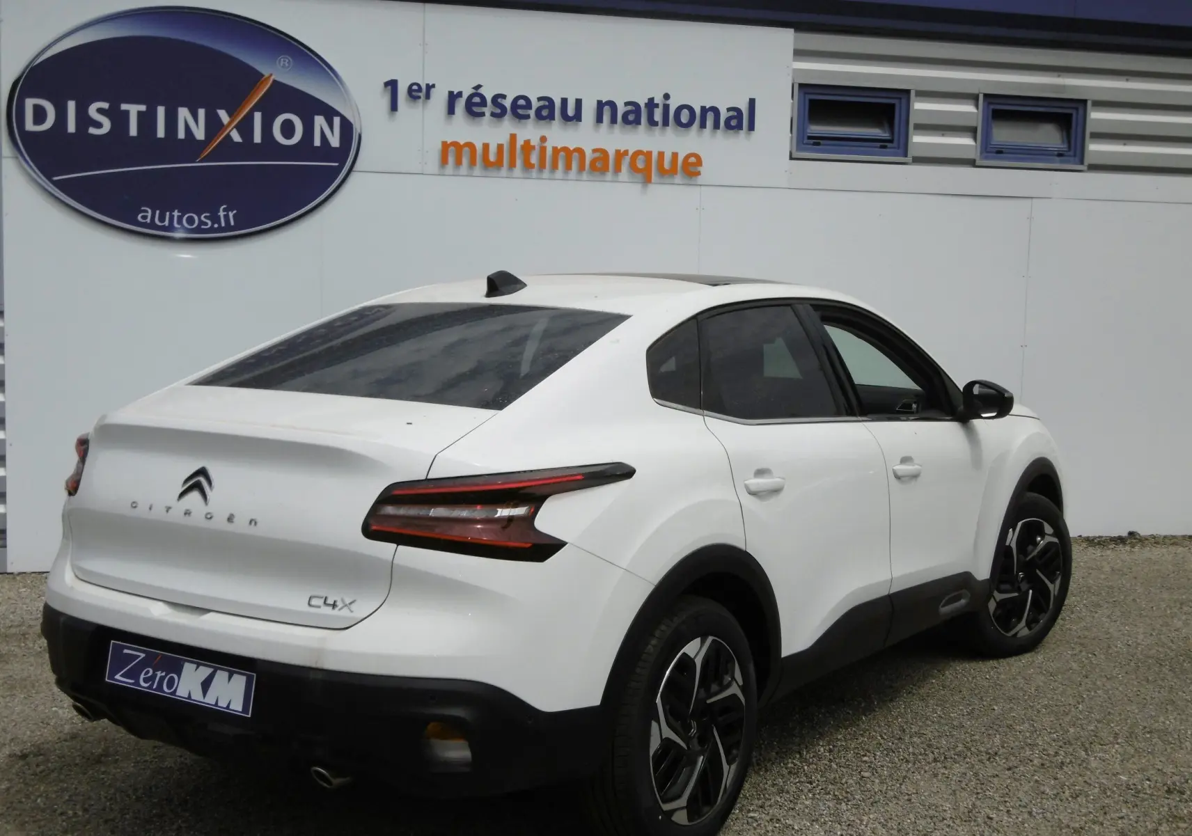 Vue 3/4 arrière droite d'une Citroën C4 X blanche polaire avec feux arrière LED et jantes bi-ton noires.