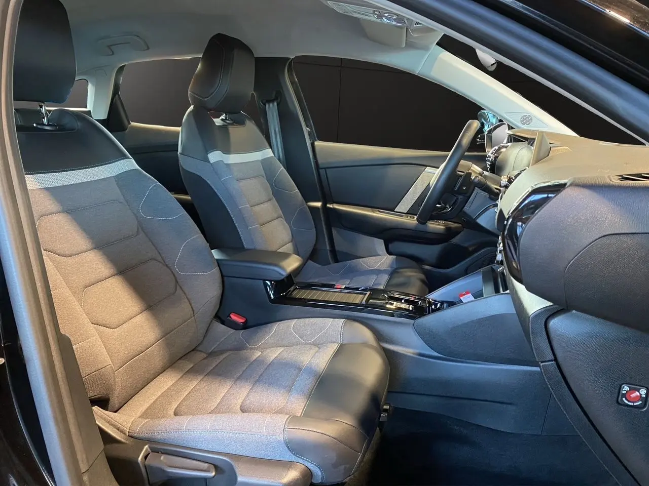 Vue intérieure côté conducteur de la Citroën C4 2023 noir Perla Nera avec sièges bi-matière gris et noir.