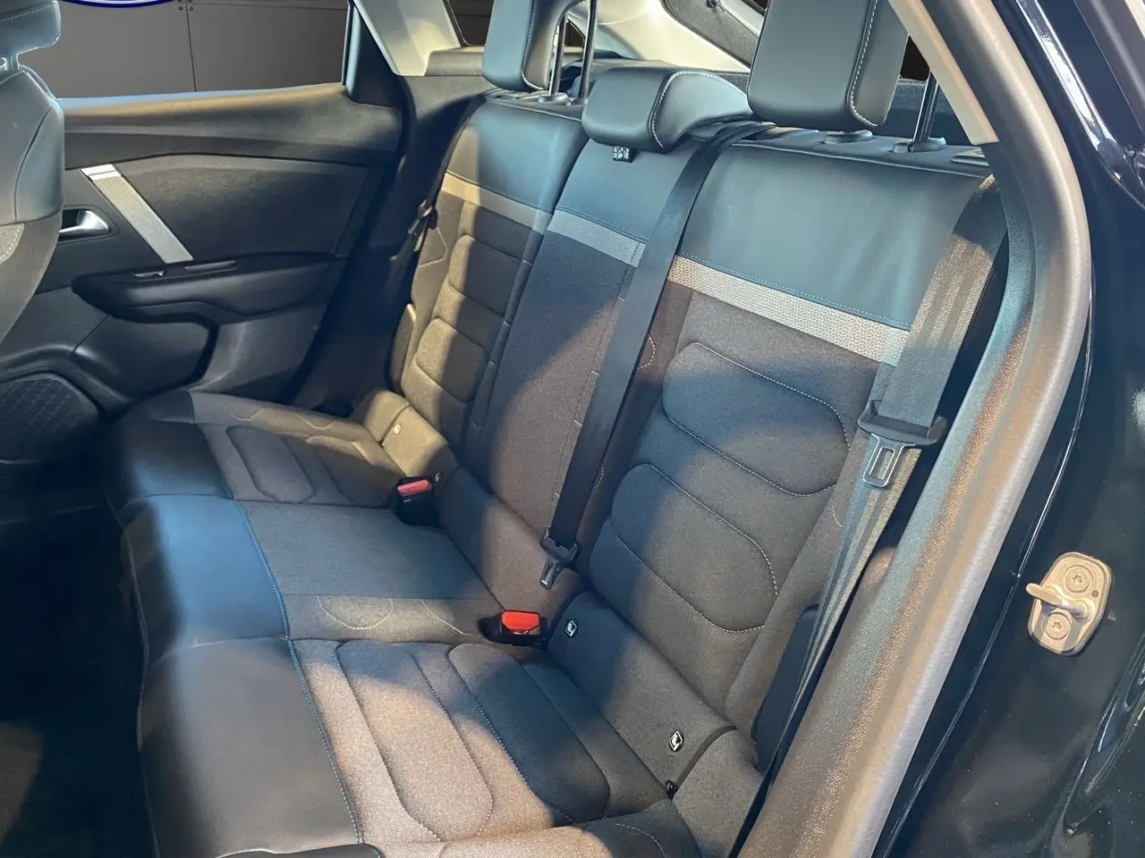 Vue latérale droite de l'intérieur arrière de la Citroën C4 2023 noir Perla Nera avec sièges en tissu et cuir gris noir.